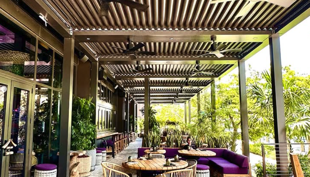 Restaurant patio with louvered pergola and dining seating
